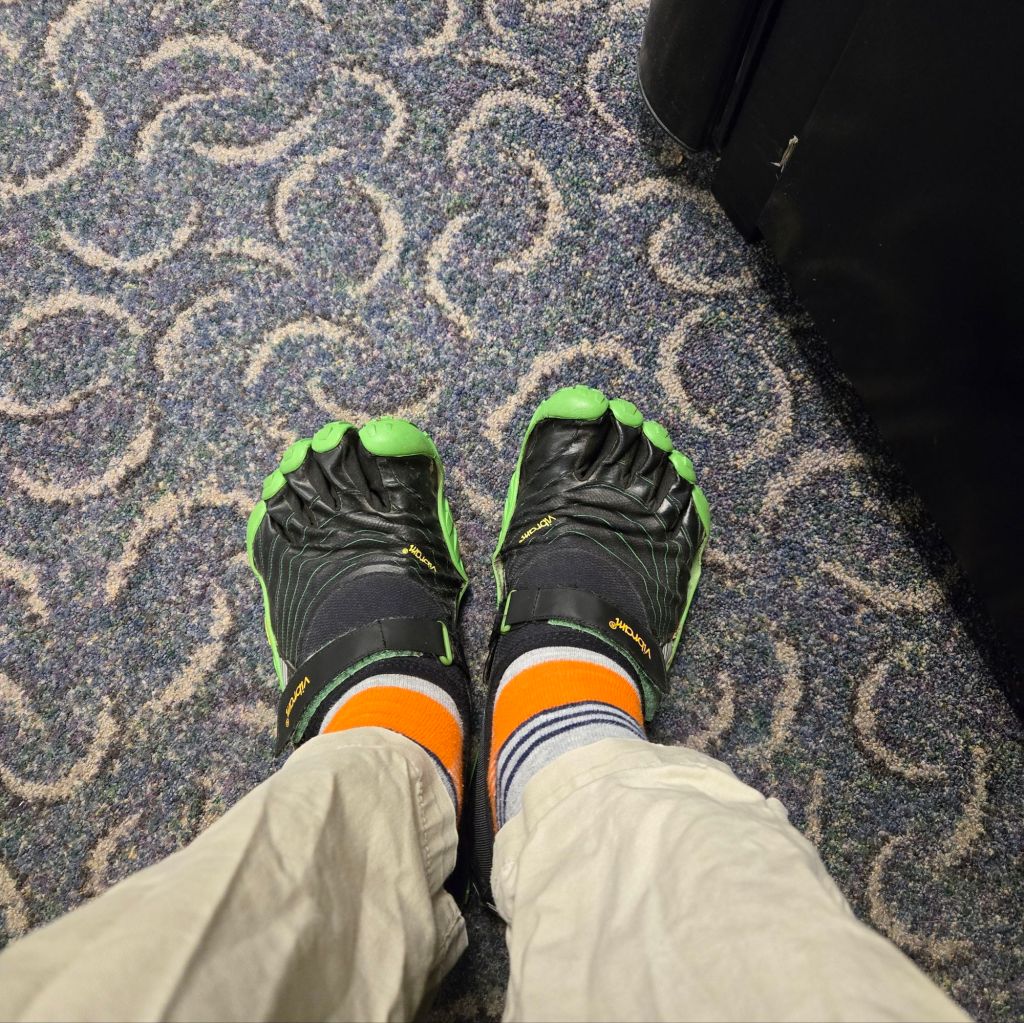 The photographer's feet, clad in colorful striped socks and a pair of Vibram toe shoes.